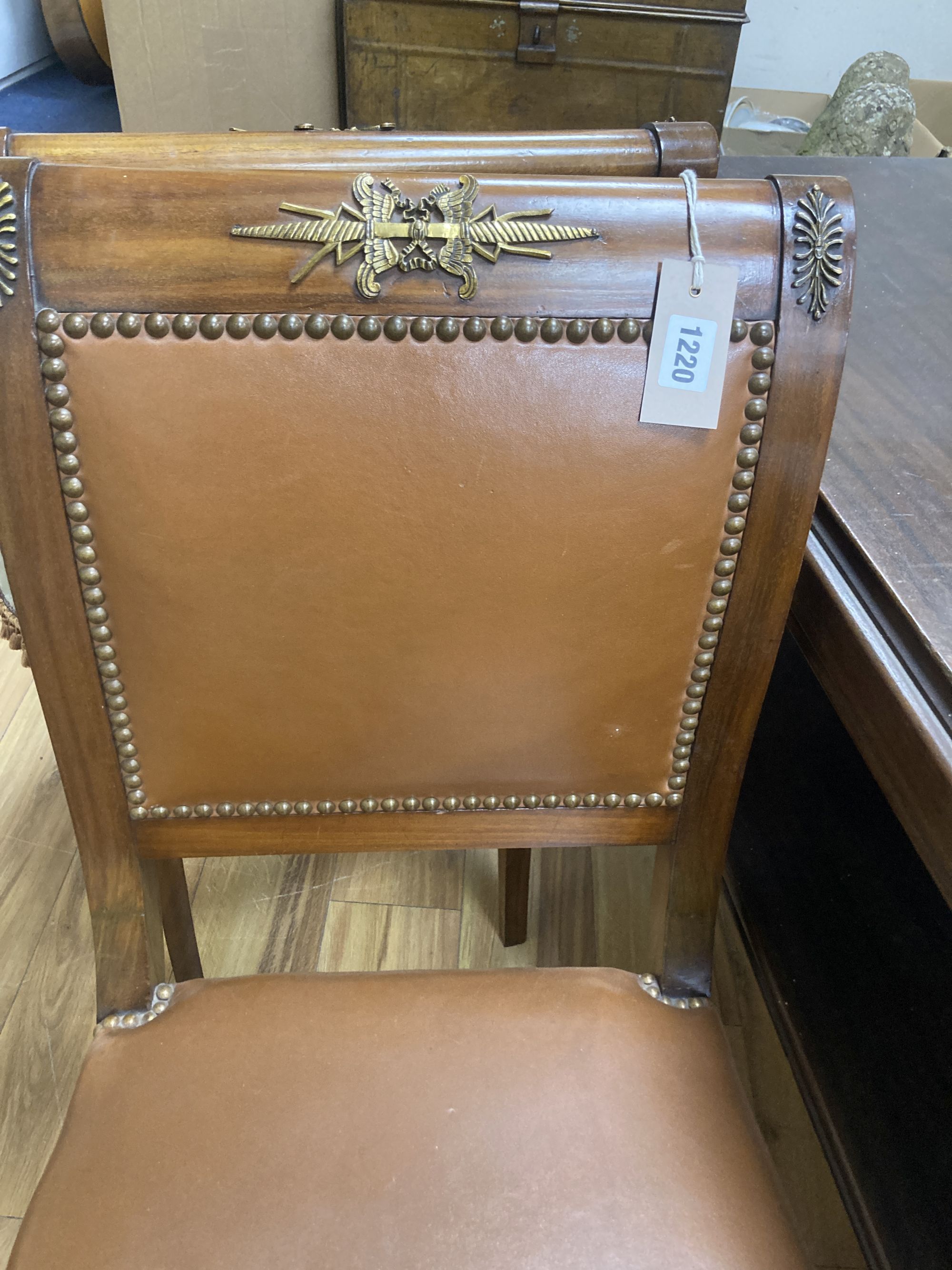 A set of six Empire style brass mounted mahogany dining chairs with tan leather upholstery